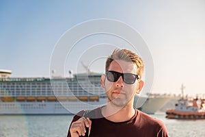 Portrait of tourist man in sunglasses standing in front of big cruise ship in port of Bar, Montenegro on Adriatic sea