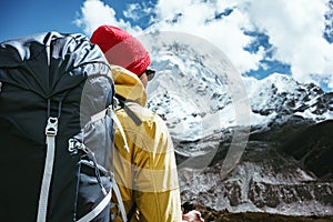 Portrait of tourist with travel backpack walk along high altitude mountain track. Outdoor mountains explorer traveling among snowy