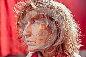 Portrait of tousled disheveled middle-aged woman looking like a madwoman on red background in studio. Actress during the