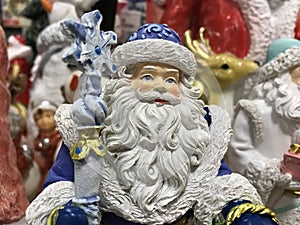 Portrait of a toy Santa Claus in a blue suit on the background of a zoot deer and other toys in the store.