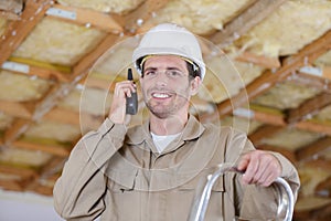 portrait tradesman using walkie-talkie while standing on stepladder