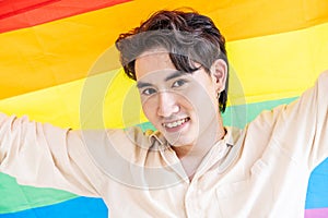 Portrait of transgender or gay man smiling in front of camera with pride rainbow flag isolated on white background with copy space