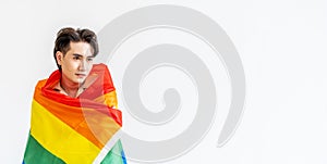 Portrait of transgender or gay man smiling in front of camera taking cover with lgbt flag on white background with copy space.