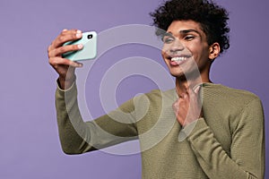 Portrait of transgender latino male taking selfies with mobile in hand. Happy trans gender young man