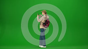 Portrait of traveler isolated on chroma key green screen background. Young girl with backpack checking the departure