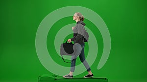 Portrait of traveler isolated on chroma key green screen background. Young girl in casual clothing walking with laptop