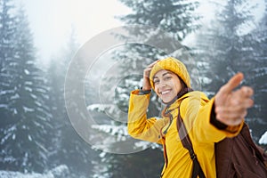 Portrait traveler woman at winter foggy forest giving hand to camera like follow me