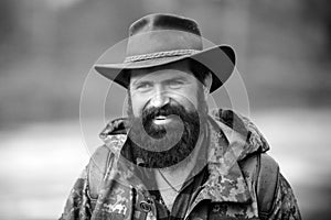 Portrait of traveller bearded man in cowboy hat. Close up portrait of happy middle aged smiling man in a countryside.