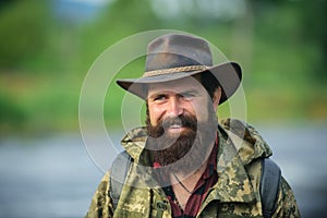 Portrait of traveller bearded man in cowboy hat. Close up portrait of happy middle aged smiling man in a countryside.