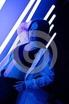 Portrait trendy young female dancer posing in the studio on a colorful background with neon lighting tube. Fashion