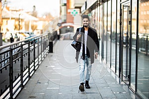 Portrait of a trendy young man with backpack walking in the city street