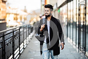 Portrait of a trendy young man with backpack walking in the city street