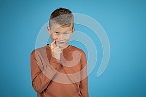 Portrait of tricky preteen boy touching chin and looking at camera