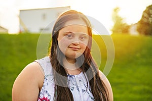 A Portrait of trisomie 21 adult girl outside at sunset