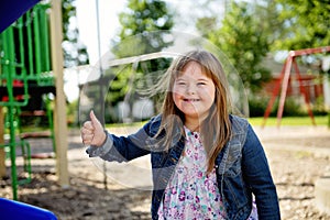 A portrait of trisomie 21 child girl outside having fun on a park