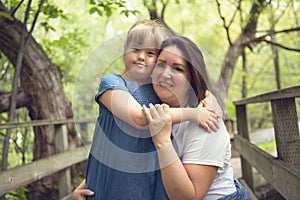 A portrait of trisomie 21 child girl outside with his mother