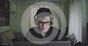 Portrait of troubled millenial sitting in front of computer working at home. Young freelancer wearing glasses frustrated