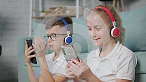 Portrait of twins girl and boy listening to music using phone and headphones