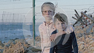 Portrait two abandoned children near border between countries. destroyed family a consequence of the war. helpless little boy and