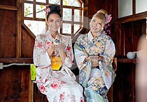 Portrait of two Asian women wear japanese style dress sit and enjoy in small shop and also hold small gift and look to camera with