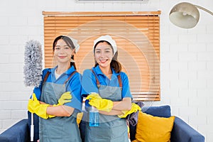 Portrait of two Asian young cleaning service women worker team working in house. Girls housekeeper cleaner, hold feather duster,