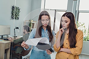 Portrait of two attractive skilled focused people experts discussing marketing plan strategy reading list at work place