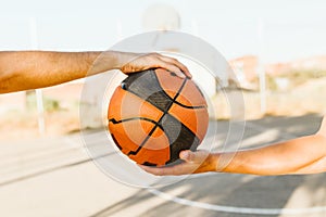 Portrait of two basketball players holding a basket ball on court.