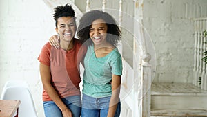 Portrait of two beautiful african american girls laughing and looking into camera at home