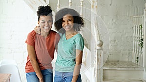 Portrait of two beautiful african american girls laughing and looking into camera at home