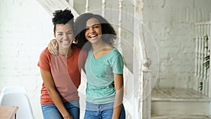 Portrait of two beautiful african american girls laughing and looking into camera at home