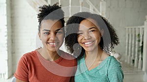 Portrait of two beautiful african american girls laughing and looking into camera at home