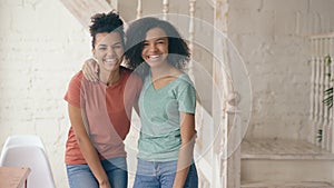 Portrait of two beautiful african american girls laughing and looking into camera. Women show emotions from serios face