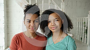Portrait of two beautiful african american girls smiling and looking into camera at home