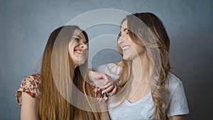 Portrait of two beautiful girls smiling and looking at camera in studio.