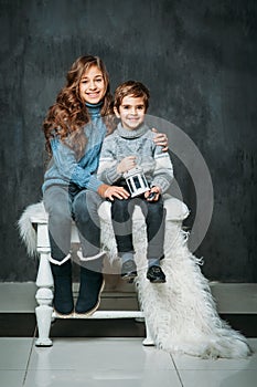 Portrait of two beautiful kids dressed in sweaters and jeans on vintage background