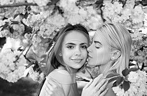 Portrait of a two beautiful spring girls. Two young women relaxing in sakura flowers. Lesbian couple kissing. Sensual