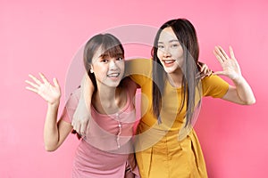 Portrait of two beautiful young asian girls posing on pink background