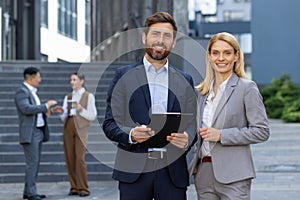 Portrait of two business partners, business people a man and a woman are smiling and looking at the camera, a