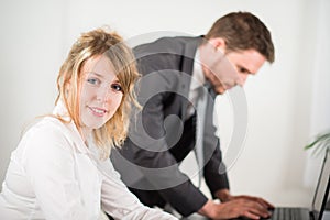Portrait of two business people working together in office with computer