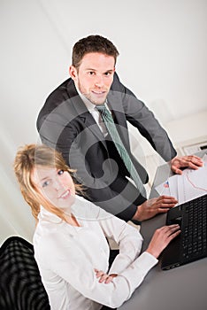 Portrait of two business people working together in office with computer