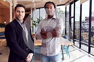 Portrait Of Two Businessmen Standing In Modern Open Plan Office Together