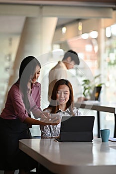 Portrait of two businesswomen are using tablet discussing planning shared project in meeting room.