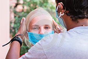 Portrait of two Caucasian and African girls in protective masks, coronavirus concept. teenage girl adjusts her friend`s medical