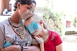 Portrait two Caucasian and African teen girls without protective masks. teen girl removes medical mask. multinational friendship.