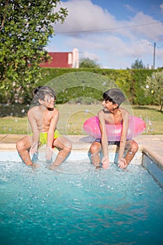 Portrait of two Caucasian boys sitting together on edge of pool