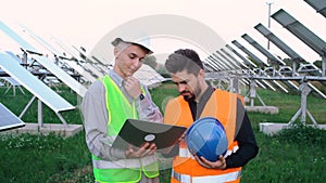 Portrait of two charismatic engineers learning the construction plan of a solar panel station.