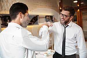 Portrait of two cheerful businessmen doing fist bump