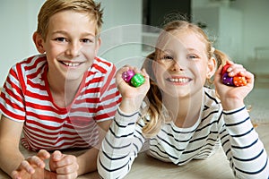 Portrait of two cheerful children laying on the floor and playing with colorful dices