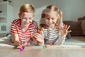 Portrait of two cheerful children laying on the floor and playing with colorful dices