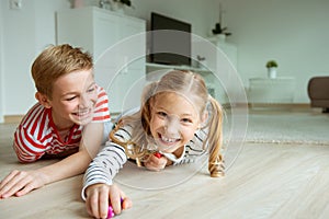 Portrait of two cheerful children laying on the floor and playing with colorful dices